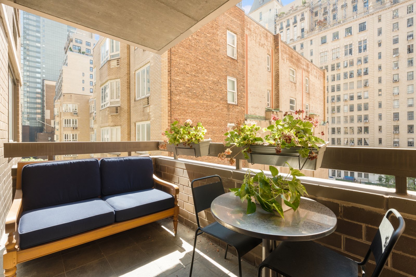 The private terrace, with a loveseat, café table, and planters, open to the south and east